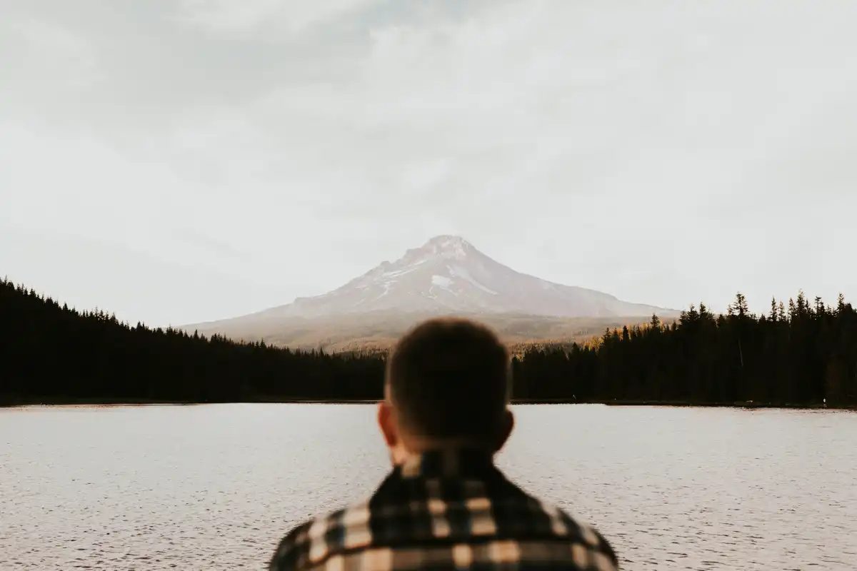 Joshua Brown seen from behind, looking across a lake toward Mount Hood.